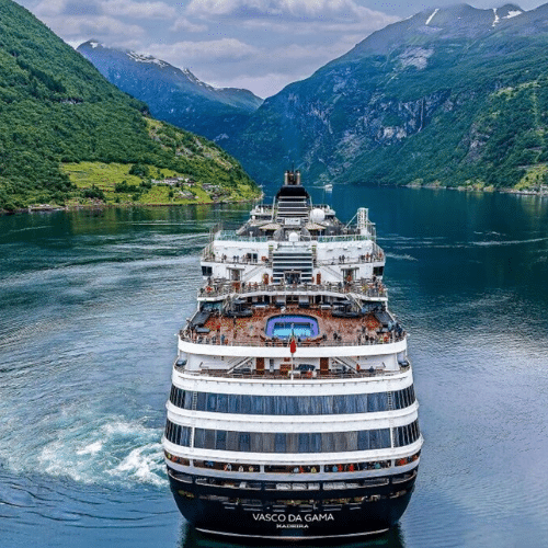 Auf dem Bild zu sehen ist das Kreuzfahrtschiff "Vasco da Gama". Es fährt mittig durch die Fjorde in Norwegen. Rechts und links sind Berge in Norwegen zu sehen.