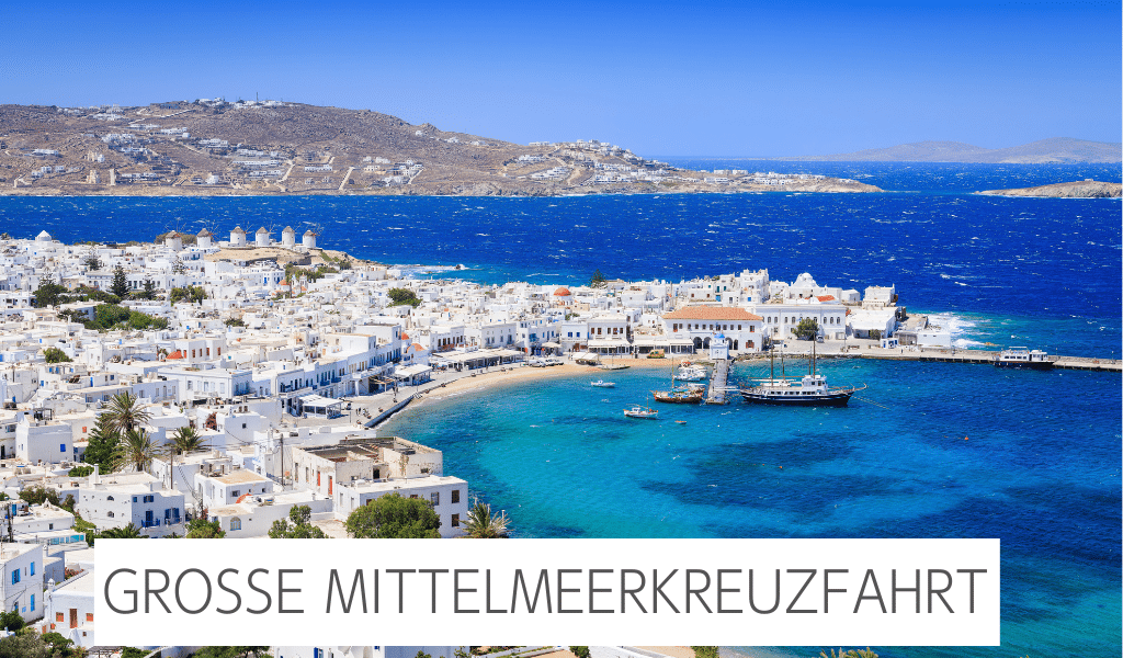 Auf dem Bild zu sehen ist Mykonos. Links im Bild ein Teil des Hafens und rechts das blaue Meer mit kleinen Fischerbooten. Im Hintergrund ist noch ein Berg zu sehen.