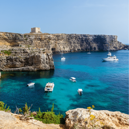 Auf dem Bild zu sehen ist die blaue Lagune von Malta. Dazwischen das blaue Meer mit sieben kleinen Booten.